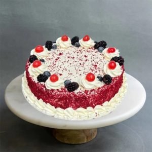 A Red Velvet Cake with swirls of cream and berries on top