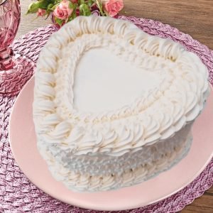 A white heart shaped wedding cake with delicate Lambeth-style vintage icing